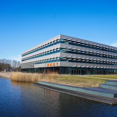 Op deze slide wordt getoond NEXT Delft, TU Delft Campus LR.